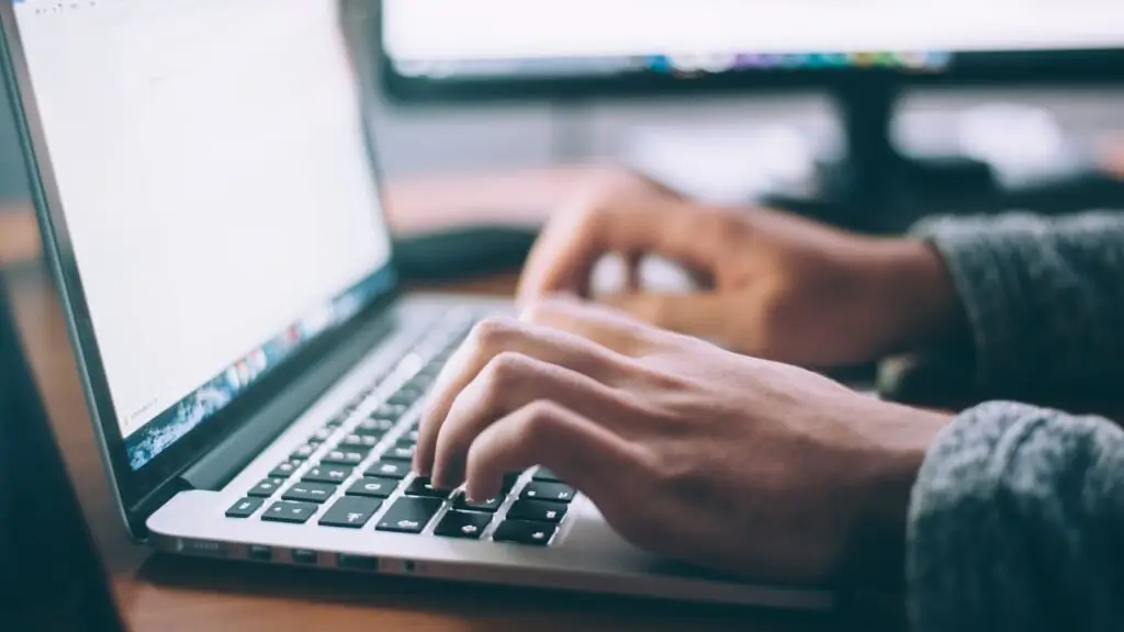 A small business owner reviewing an email newsletter draft on a laptop at a shop counter.