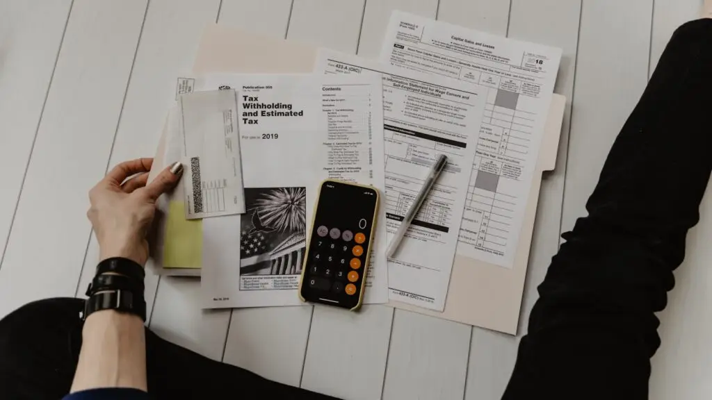 A small business owner reviews a marketing budget spreadsheet on a laptop at a bright office desk.