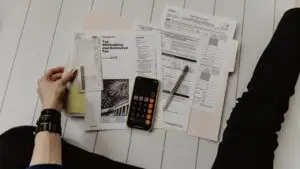 A small business owner reviews a marketing budget spreadsheet on a laptop at a bright office desk.