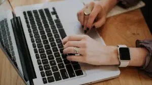A small business owner reviewing a list of search keywords on a laptop next to a notepad.