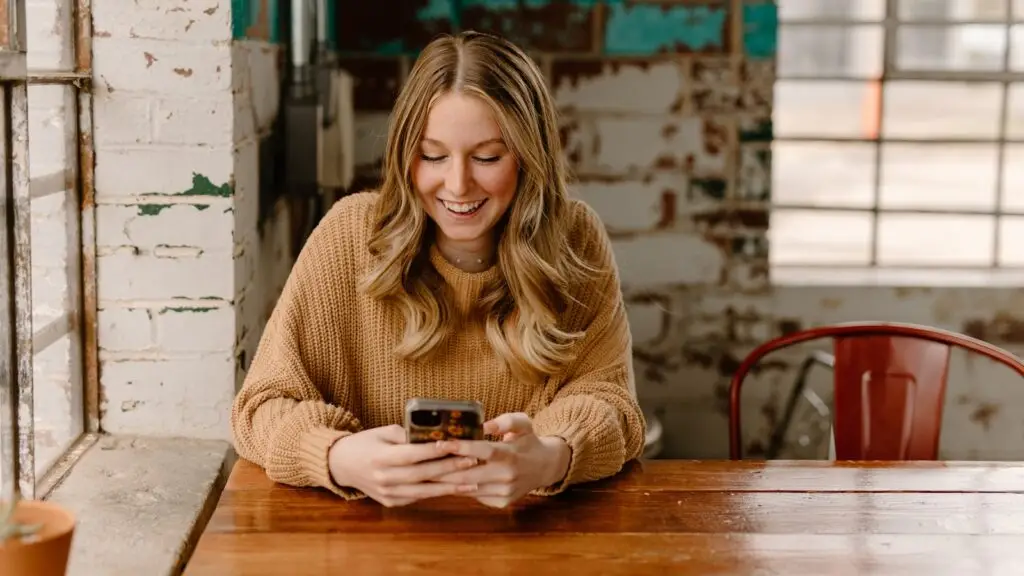 Small business owner reading a five-star review on a phone at the front counter